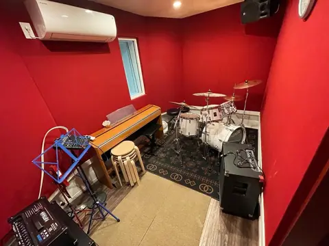 Studio 5（Rescue5 Music Academy）：ドラムと電子ピアノのある赤い壁の練習室